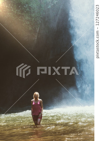 Woman walking in the water in front of the waterfall in Bali isl 127246023