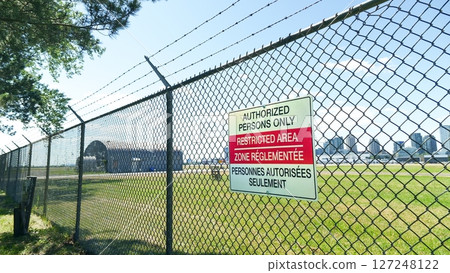 Restricted area with fence boundary and barbed wire, airport secured zone marking. Outdoor 127248122