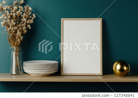 Picture Frame in home interior settings. Empty image border on wooden table. White vertical blank framework mock up with golden decorations vases on emerald green wall background. Paper page mock-up 127248841