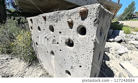 Grey concrete block with holes and metal inserts outdoor daylight Grey concrete block with holes and metal inserts outdoor daylight 127248884