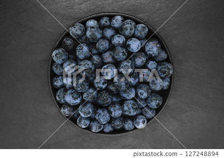Blueberries on black stone background 127248894