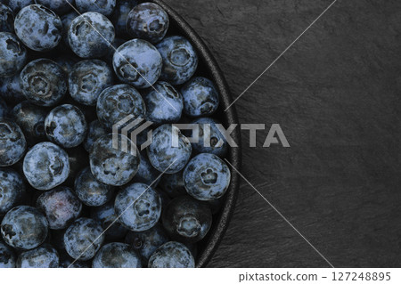 Blueberries on black stone background 127248895