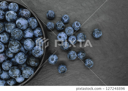 Blueberries on black stone background 127248896