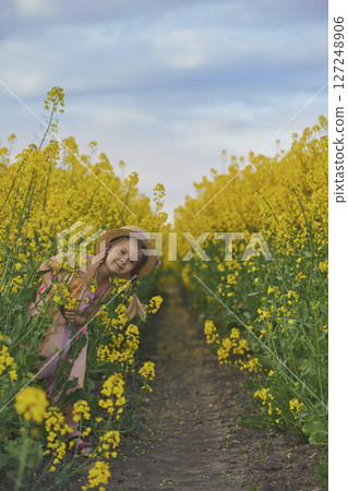 charming child in sundress in a rapeseed field charming child in sundress in a rapeseed field 127248906