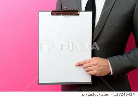 Businessman in a business suit showing a blank clipboard. Clean white sheet of paper on a pink. Front view, copy space. Clip board mockup. Writing minimalist design for notes, lists, versatile usage 127249424