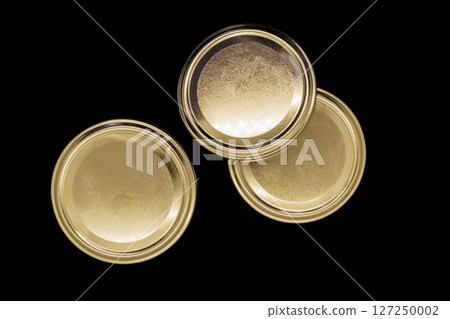 Golden jar lids isolated on black background 127250002