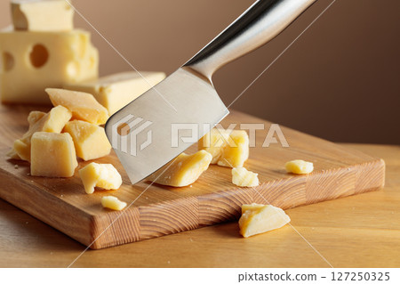 Parmesan cheese and knife on a cutting board. Parmesan cheese and knife on a cutting board. 127250325
