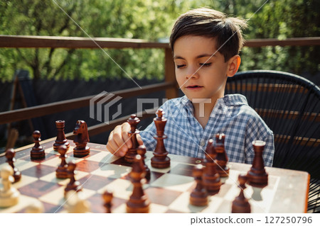 Smart child boy playing board game - chess. Moves with a bishop, intellectual 127250796