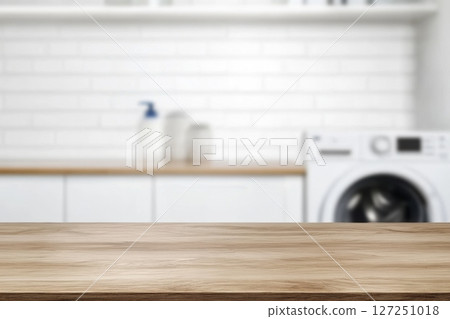 Empty horizontal wooden table for product placement in a laundry room. Flat blank tabletop surface for product display montage or counter with a blurred washing machine background. Fresh laundry. 127251018
