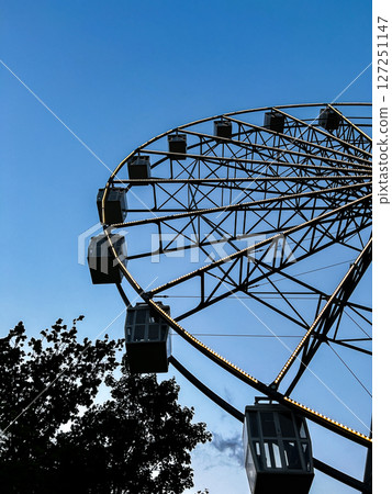 Silhouette of carnival Ferris wheel shot from below, with dynamic energy. Perfect for festival posters, funfair ads, and joyful lifestyle imagery. 127251147