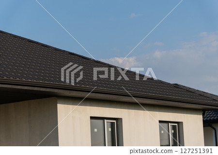 A newly installed roof on a contemporary home is shown against a clear blue sky, highlighting its sleek design and architecture 127251391