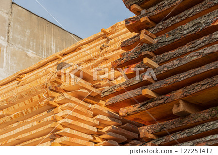Freshly cut timber is neatly stacked at a construction site, soaking up sunlight in the early afternoon hours for drying Freshly cut timber is neatly stacked at a construction site, soaking up sunlight in the early afternoon hours for drying 127251412