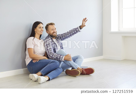 Happy couple sitting in new apartment planning interior repair and design project of new house 127251559