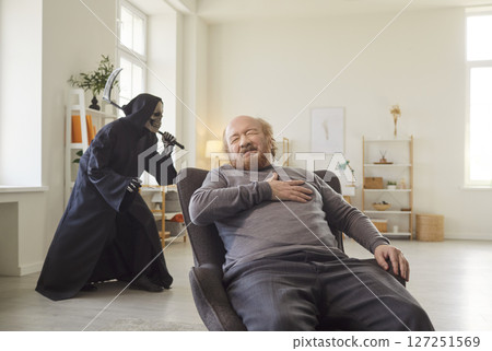 Senior man experiencing heart attack while grim reaper sneaking behind symbolizing imminent death. 127251569
