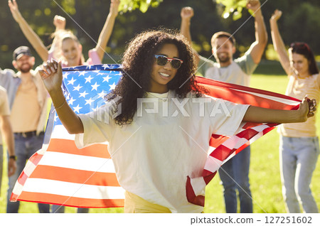 Portrait of happy woman holding usa flag celebrating Independence Day outdoors 127251602