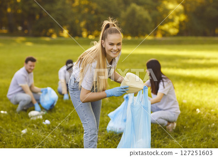 People volunteers cleaning trash from the grass in the summer park outdoors. People volunteers cleaning trash from the grass in the summer park outdoors. 127251603