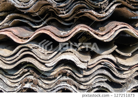 A Lot of Old Wavy Slates for Roof Placed on Each Other and Covered with Moss and Lichens 127251873