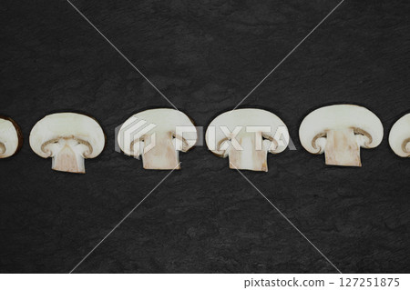 Abstract composition of split up brown champignons mushrooms placed in line on stone background surface 127251875