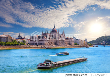 Scenic view of the Parliament of Hungary and Danube River cruise ships under dramatic evening sky, Budapest 127253038