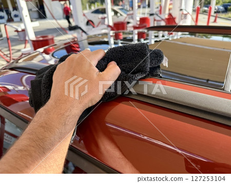 Man hand cleaning car with microfiber cloth at car wash Man hand cleaning car with microfiber cloth at car wash 127253104