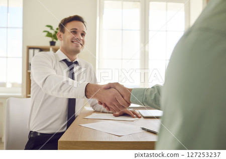 Two happy business partners meet in the office, make a deal and exchange handshakes 127253237