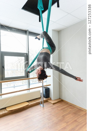 Graceful woman upside down in aerial silk backbend pose. 127253386