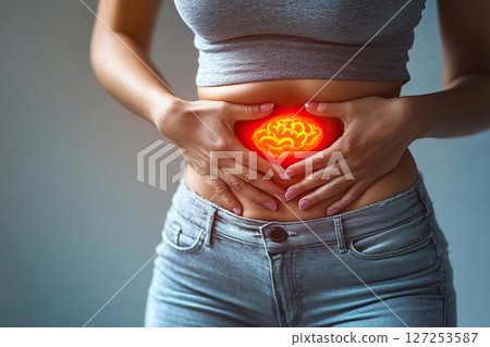 Close-up of a woman holding her stomach in pain with a glowing red color area of her belly. Generated by artificial intelligence 127253587