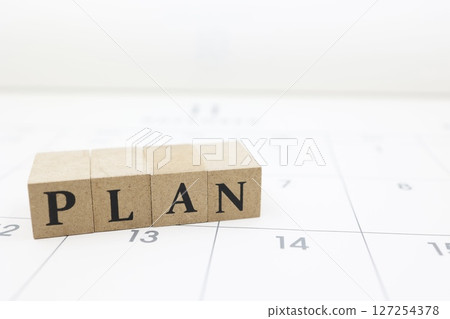 A block with the word PLAN written on it placed on top of a calendar 127254378