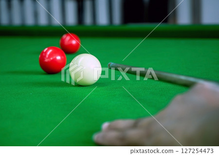 A snooker player is aiming at the white cue ball. A snooker player is aiming at the white cue ball. 127254473
