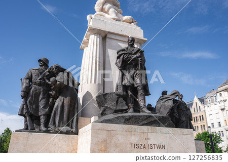 The Tisza Istvan Memorial in Budapest, Hungary, features a central statue of Count Istvan Tisza, surrounded by sculptures and historic buildings under clear skies. 127256835