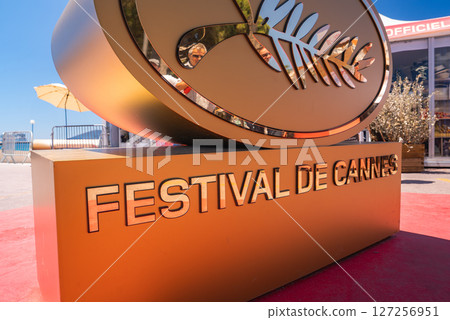 Golden palm leaf sculpture with 'Festival de Cannes' text on its base, set on a red carpet outdoors in Cannes, France, during the film festival. 127256951