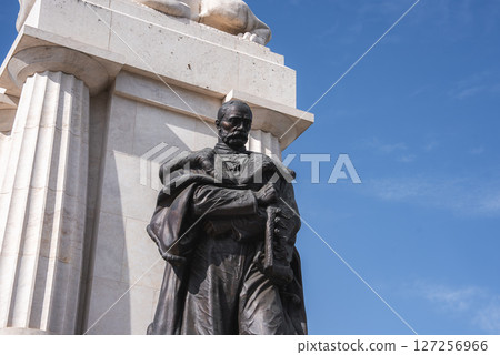 The Tisza Istvan Memorial. A bronze statue of a man in formal attire holding a scroll stands on a white stone pedestal with fluted columns and a sculpted lion in Budapest, Hungary. The Tisza Istvan Memorial. A bronze statue of a man in formal attire holding a scroll stands on a white stone pedestal with fluted columns and a sculpted lion in Budapest, Hungary. 127256966