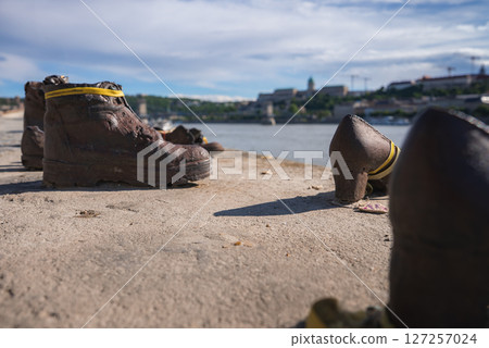 The Shoes on the Danube Bank Holocaust memorial in Budapest, Hungary, with bronze shoes along the riverbank, Buda Castle, and Chain Bridge in the background. The Shoes on the Danube Bank Holocaust memorial in Budapest, Hungary, with bronze shoes along the riverbank, Buda Castle, and Chain Bridge in the background. 127257024