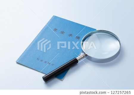 藍色背景中的退休金書和放大鏡 藍色背景中的退休金書和放大鏡 127257265