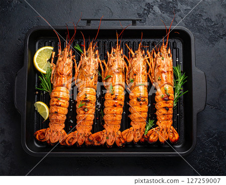AI generated top view of fresh mantis shrimp grilled over charcoal, perfectly cooked with smoky aroma and succulent meat. Seasoned with salt and black pepper, garnished with rosemary and lemon slices. 127259007