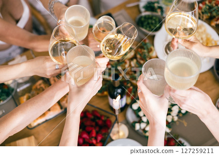 Group of people clinking glasses over festive lunch table with wine, cheese, bruschetta, strawberrie 127259211