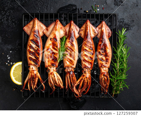 AI generated top view of fresh beka squid grilled over charcoal, perfectly cooked with tender texture and light smoky aroma. Seasoned with salt and black pepper, garnished with rosemary sprigs. 127259307