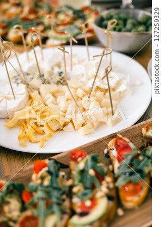 Close-up of assorted cheese platter with skewers, bruschetta on rustic table for festive appetizer 127259329