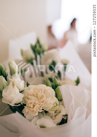 Close-up of white flower bouquet with soft background, wrapped in paper, romantic floral decor Close-up of white flower bouquet with soft background, wrapped in paper, romantic floral decor 127259335