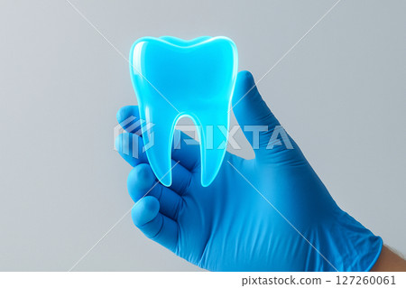 AI generated image of a gloved medical hand gently holding a translucent glowing blue tooth symbolizing precision care and futuristic dental technology in a clean clinical setting 127260061