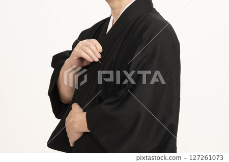 A man dressing himself in a kimono, adjusting the collar of his kimono A man dressing himself in a kimono, adjusting the collar of his kimono 127261073