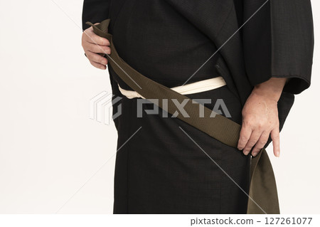 一名男子穿著和服,將腰帶繫在身前 一名男子穿著和服,將腰帶繫在身前 127261077