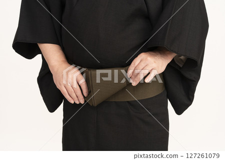一名男子穿著和服，在身體前方繫上腰帶 127261079