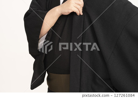 A man dressing himself in a kimono A man dressing himself in a kimono 127261084
