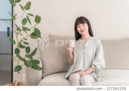 一位輕鬆的亞洲女性,早上在家用杯子喝茶和熱水(Onkatsu) 一位輕鬆的亞洲女性,早上在家用杯子喝茶和熱水(Onkatsu) 127261150