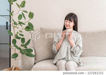 一位輕鬆的亞洲女性,早上在家用杯子喝茶和熱水(Onkatsu) 一位輕鬆的亞洲女性,早上在家用杯子喝茶和熱水(Onkatsu) 127261151