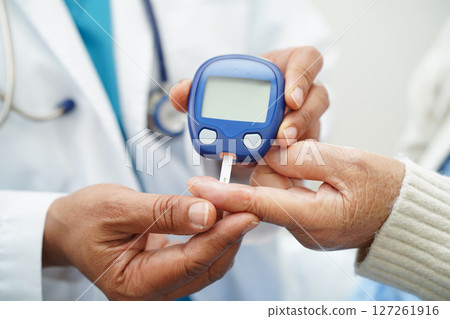 Asian doctor using digital glucose meter for check sample blood sugar level to treatment diabetes. Asian doctor using digital glucose meter for check sample blood sugar level to treatment diabetes. 127261916
