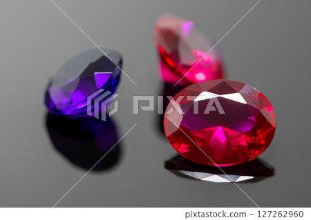 Red rubies and purple amethyst gemstones on black reflective surface Red rubies and purple amethyst gemstones on black reflective surface 127262960