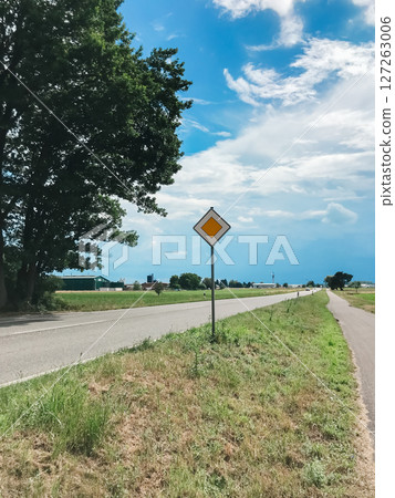 A yellow and white sign is on the side of a road 127263006