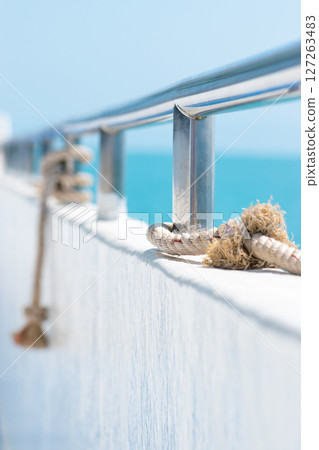 Ship railing with rope and blue sea Ship railing with rope and blue sea 127263483